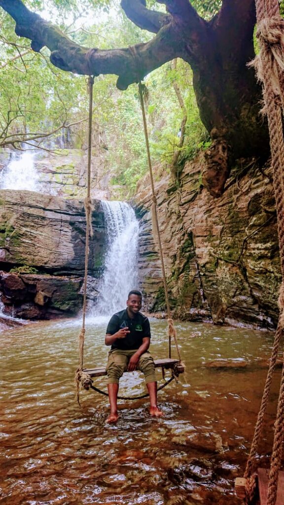 A Fasta Travel guide sitting on a rope swing in front of Choma Waterfall on the Uluguru hike