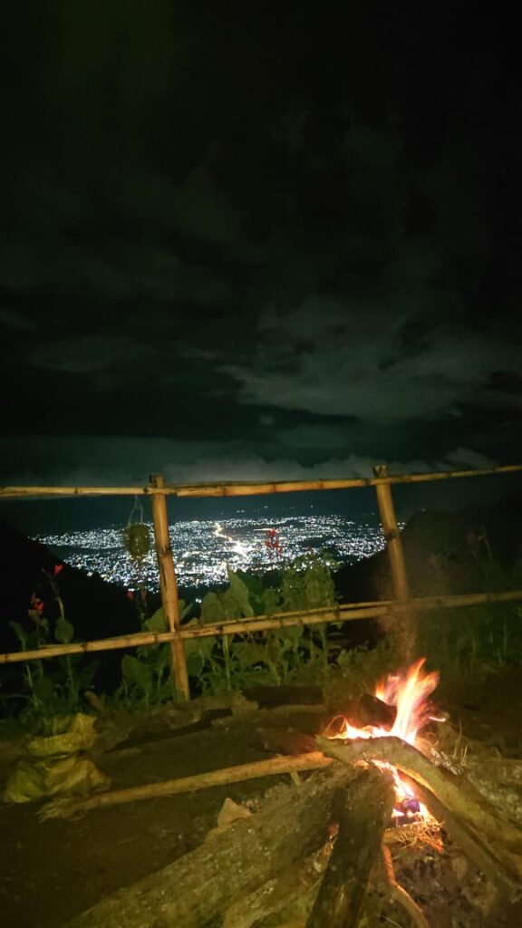 A campfire at night at Morning Site with the lights of Morogoro town visible far below