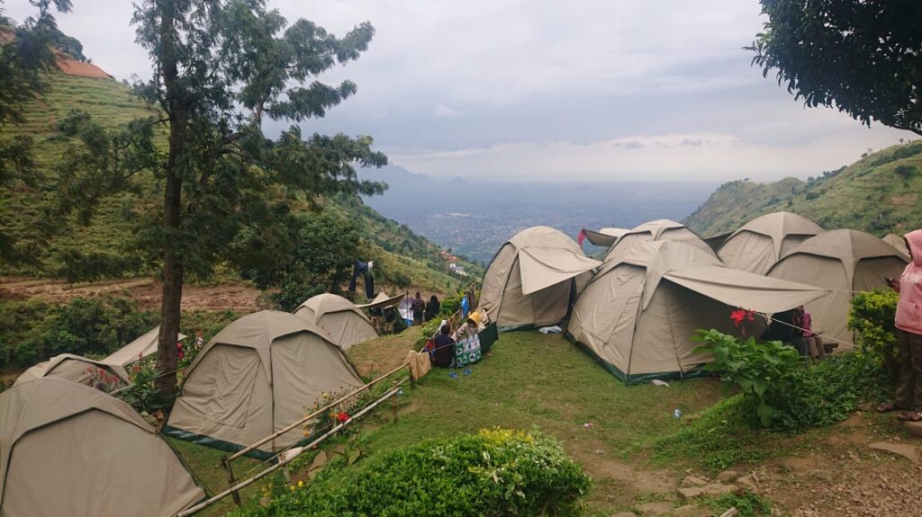 A row of tents set up on a ridge in the Uluguru Mountains with Morogoro town visible in the valley below